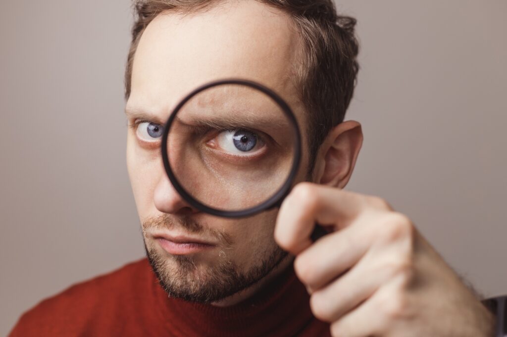 Man suspiciously looking through magnifier