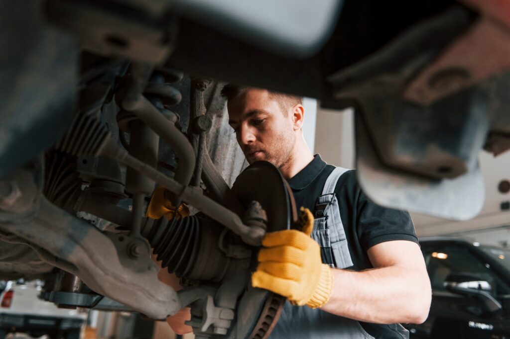 Professional service. Man in uniform is working in the auto service